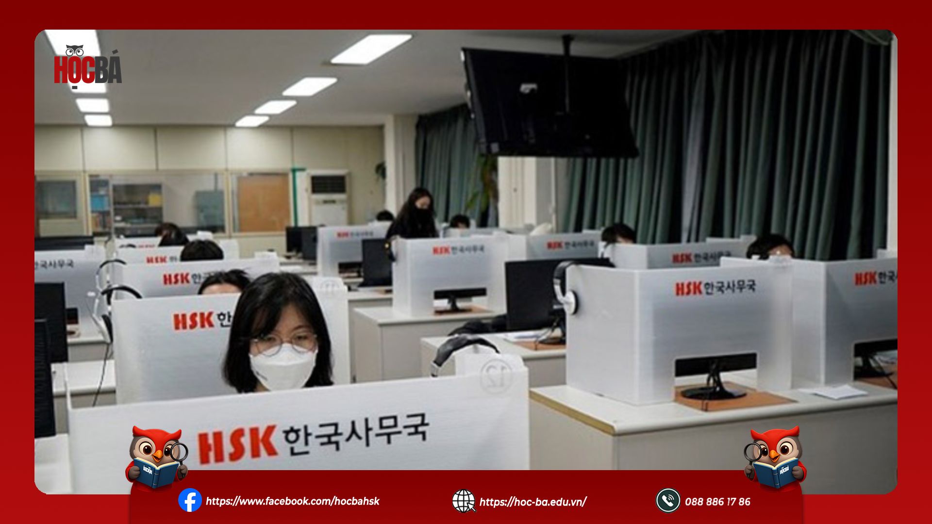 Các thí sinh đeo khẩu trang và tai nghe đang tập trung làm bài thi nói HSKK trên máy tính tại các vách ngăn của phòng thi.